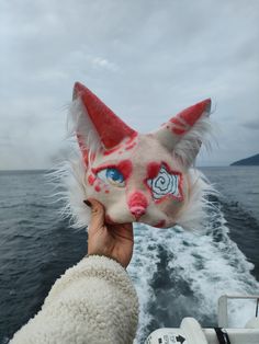 a person holding up a stuffed animal on the back of a boat