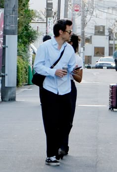 a man and woman walking down the street with one holding a cup in his hand