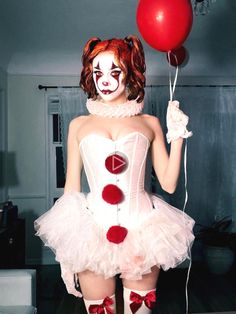 a woman dressed up as a clown holding a red ballon and wearing white dress