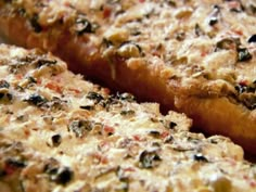 close up view of bread with various toppings on it's surface, including black olives