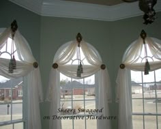 three windows with white curtains in front of them