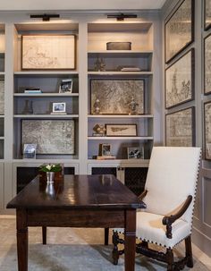 a desk with chairs and bookshelves in a room that has many pictures on the wall