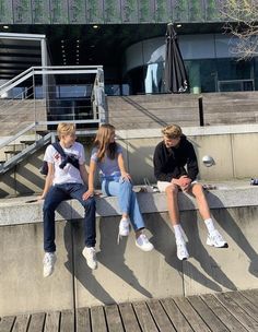 three young people sitting on concrete steps outside