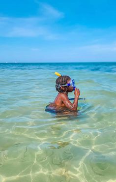 a person in the water with a yellow frisbee on their head and one eye closed