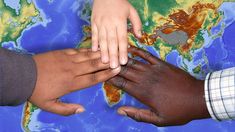 three people holding hands over a map of the world with each other's hands