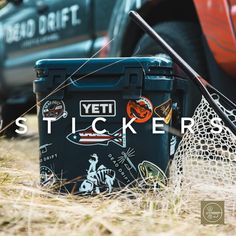 a cooler sitting in the grass next to a red truck with stickers on it