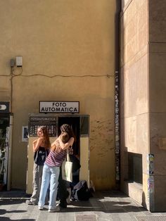 two women are standing in front of an atm