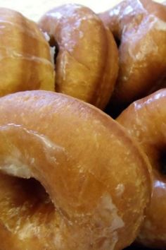 a pile of glazed donuts sitting on top of a table next to each other