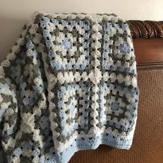 a crocheted blanket sitting on top of a couch next to a brown chair