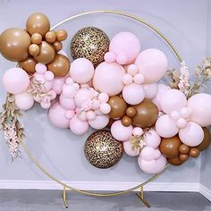 balloons and flowers are arranged in a circle on the wall behind a round metal stand