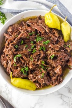 a white bowl filled with shredded beef and garnished with parsley on top