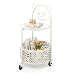 a white shelf with books and magazines in it on top of a metal rack filled with flowers