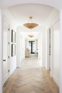 an empty hallway with white walls and wood flooring is seen from the entry way