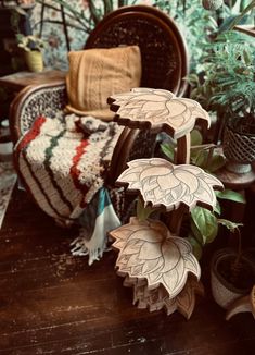 three wooden flowers sitting on top of a table next to potted plants and blankets