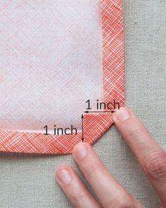 someone is measuring the width of a piece of fabric with one hand and two fingers