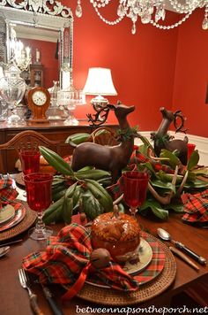 the table is set for christmas dinner with deer figurines and plaid napkins