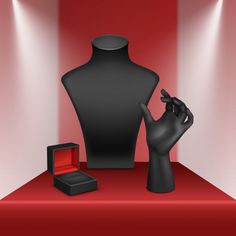 a black mannequin, ring and box on a red carpet with spotlights