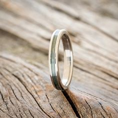 a wedding ring sitting on top of a piece of wood with a thin band in the middle