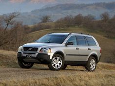 a silver volvo suv parked on the side of a dirt road in front of mountains