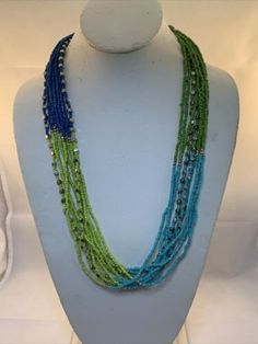 "Vintage 26\"-29\" 10 Strand Beaded Necklace. It is green, aqua blue and blue. It has a lobster clasp. It comes with a gift box. (Jewelry Tub 4 # 1820) USA Seller!! Estate sale find. We do not polish our estate treasures/vintage jewelry. Come Check out our Ebay store at Stores.ebay.com/gtnm1869. We also have vintage jewelry, Christmas ornaments, vintage glassware and many other items. We will combine shipping for multiple items if possible." Green Beaded Necklace With Lobster Clasp As Gift, Adjustable Blue-green Beaded Jewelry, Turquoise Faceted Beads Costume Jewelry Necklace, Turquoise Faceted Beaded Costume Jewelry Necklace, Turquoise Faceted Beads Costume Necklace, Green Necklaces With Lobster Clasp And Round Beads, Handmade Blue-green Beaded Necklaces, Green Multi-strand Beads For Gifts, Blue Costume Jewelry Beaded Necklace With Faceted Beads