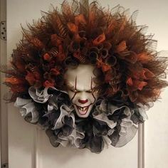 a creepy clown mask hanging on the front door with hair around it's face