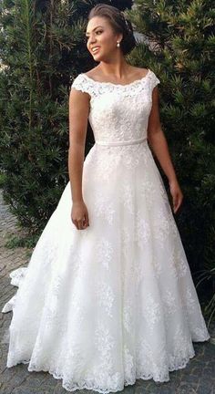 a woman standing in front of a bush wearing a wedding dress