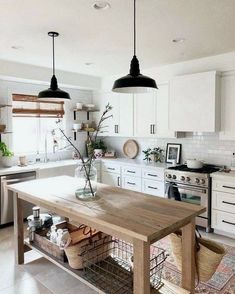 a kitchen with white cabinets and an island in the middle, surrounded by hanging lights