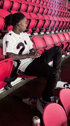 a man sitting in the bleachers with his feet up and one hand on his hip