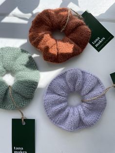 three knitted scrunffles are on the table with tags attached to them