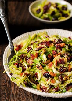 a white bowl filled with lettuce and cranberries on top of a wooden table