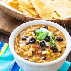 a white bowl filled with black beans and tortilla chips on top of a table