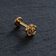 a pair of gold cufflinks with a rose on the end, sitting on a black surface