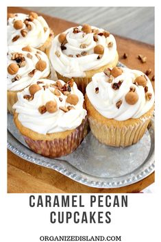 several cupcakes with white frosting and nuts on a silver plate next to a napkin