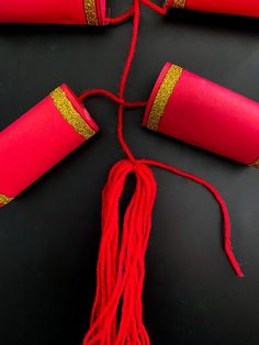 red and gold decorations on black surface with string hanging from it's end,