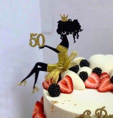 a cake decorated with strawberries, blackberries and gold glitter is sitting on a table