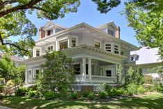 a large white house sitting on top of a lush green field