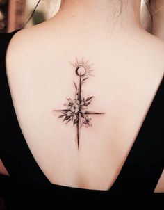 a cross tattoo on the back of a woman's upper arm and shoulder with flowers