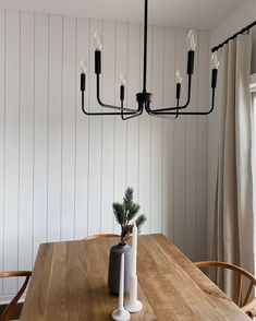 a dining room table with a vase and candle holder on it, next to a window