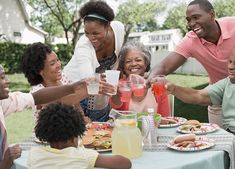 a group of people sitting around a table with plates of food and drinks in front of them