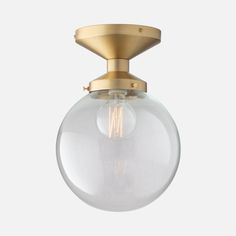 an antique brass ceiling light with clear glass globe