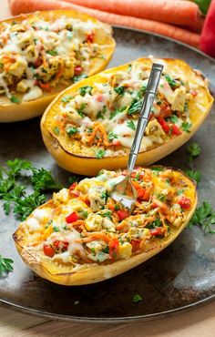 three stuffed squash halves on a plate with carrots in the background