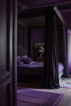 a bedroom with purple walls and curtains on the bed