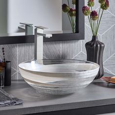 there is a bowl sink on the counter in this bathroom, with flowers and soap