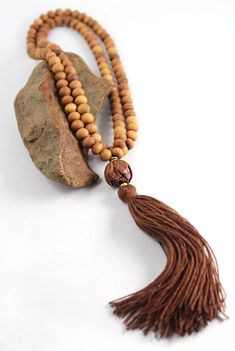 Available in both knotted or unknotted style, these natural sandalwood mala beads have a subtle woodsy fragrance. Since ancient times the scent of Sandalwood has been used to calm the mind and enhance meditation practice. As the beads move through your fingers, a soft fragrance wafts from them. Exquisite! Perfect for men or women! A nicely carved lotus flower and natural fibre tassel make for a nice light weight strand. Bead size is approx. 7-8mm with 108 beads in the strand. A perfect mala neck Collar Hippie, Sandalwood Mala, Yoga Beads, Mala Bead Necklace, Beads Mala, Meditation Beads, Yoga Style, Beaded Tassel Necklace, Daily Meditation