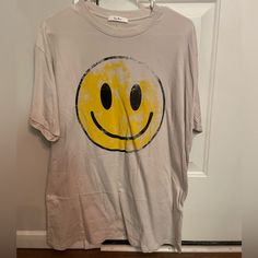 a t - shirt with a smiley face drawn on it hanging from a hanger