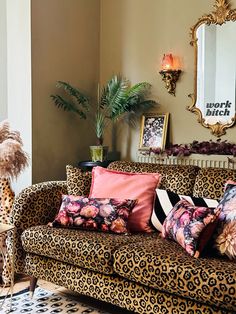 a leopard print couch in a living room with pink and black pillows on top of it