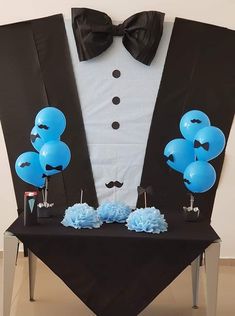 a tuxedo suit and bow tie with blue balloons on a black table cloth