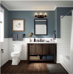 a white toilet sitting next to a sink in a bathroom under a framed painting on the wall