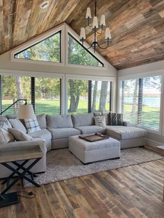 a living room filled with lots of furniture under a wooden ceiling mounted window sill