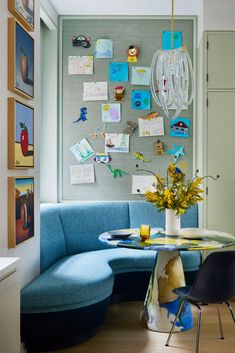 a blue couch sitting in front of a table next to a wall with pictures on it